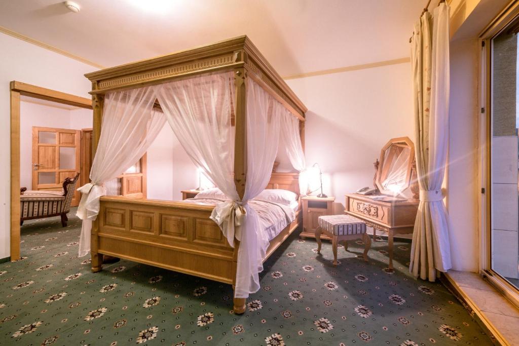 StrážaHotel Diana的一间卧室配有天蓬床和镜子