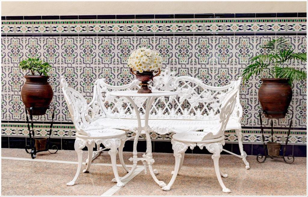 塞维利亚金橙花旅馆的一张白色的桌子和两把椅子以及一张带鲜花的桌子