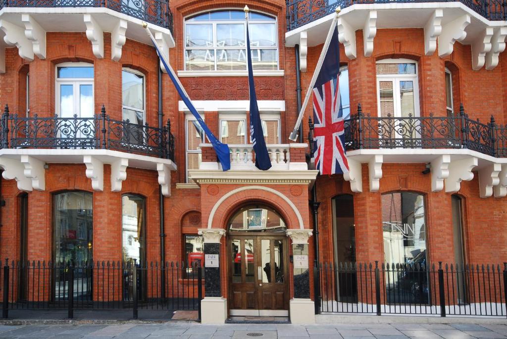 伦敦The Harrington - Gloucester Road - 1 Harrington Gardens的砖楼前悬挂两面旗帜