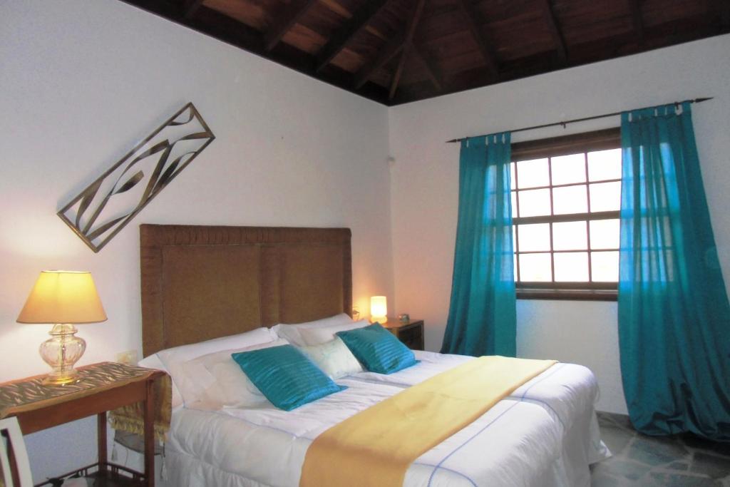 阿罗纳芬卡奇玛卡酒店的一间卧室配有一张带蓝色窗帘的床和一扇窗户