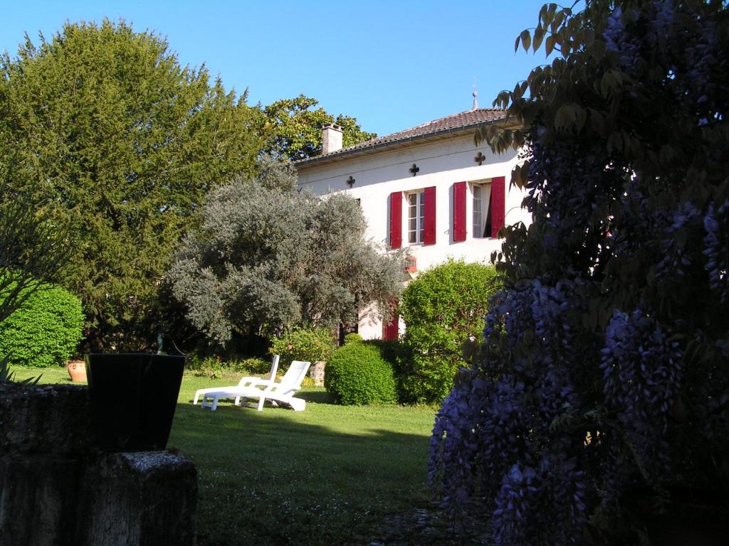 蒙卡雷阿勒奥利维尔住宿加早餐旅馆的院子里的白色房子,有红色百叶窗和白色椅子