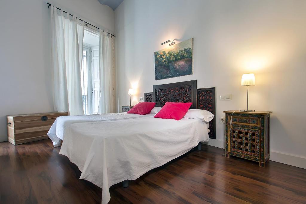 塞维利亚金特罗公寓酒店的一间卧室配有一张大床和两个红色枕头