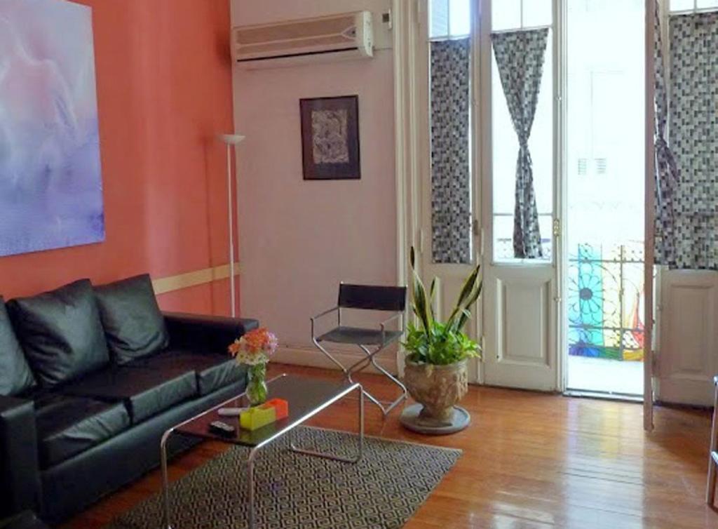 布宜诺斯艾利斯LGY G A Y Bed & Breakfast ONLY MEN的客厅设有黑色沙发和橙色墙壁。