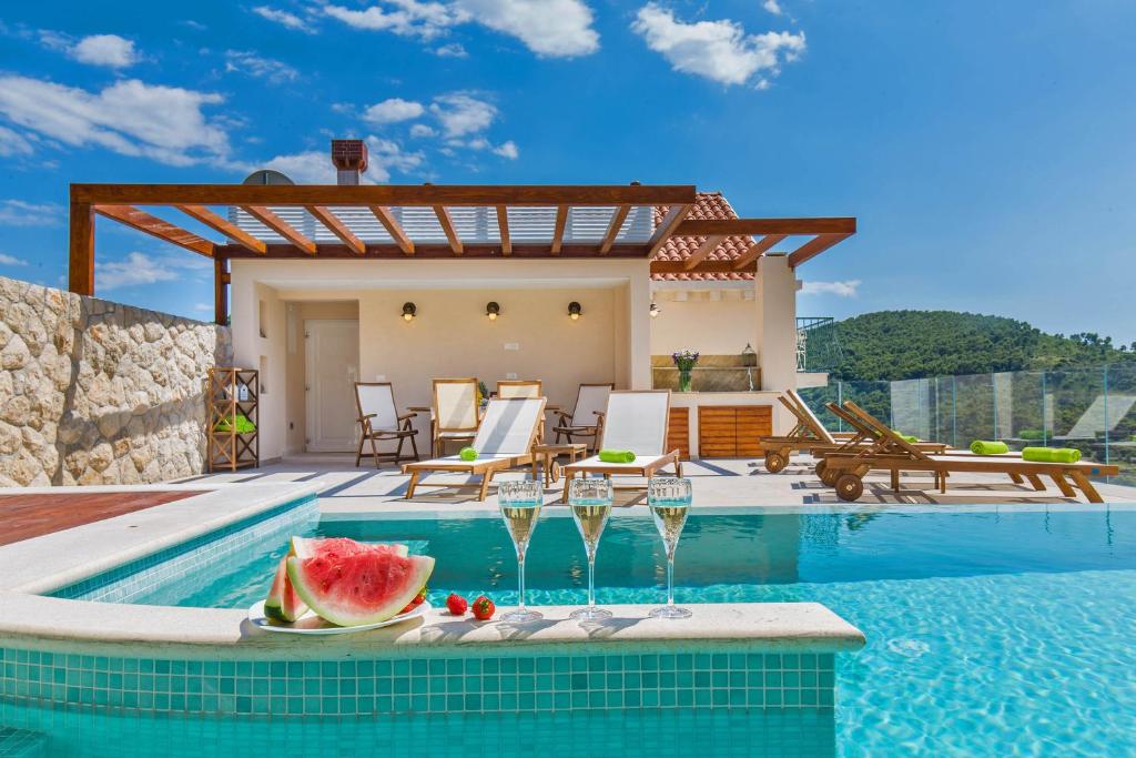 杜布罗夫尼克Villa Boban的别墅,设有游泳池,餐桌上放着西瓜片