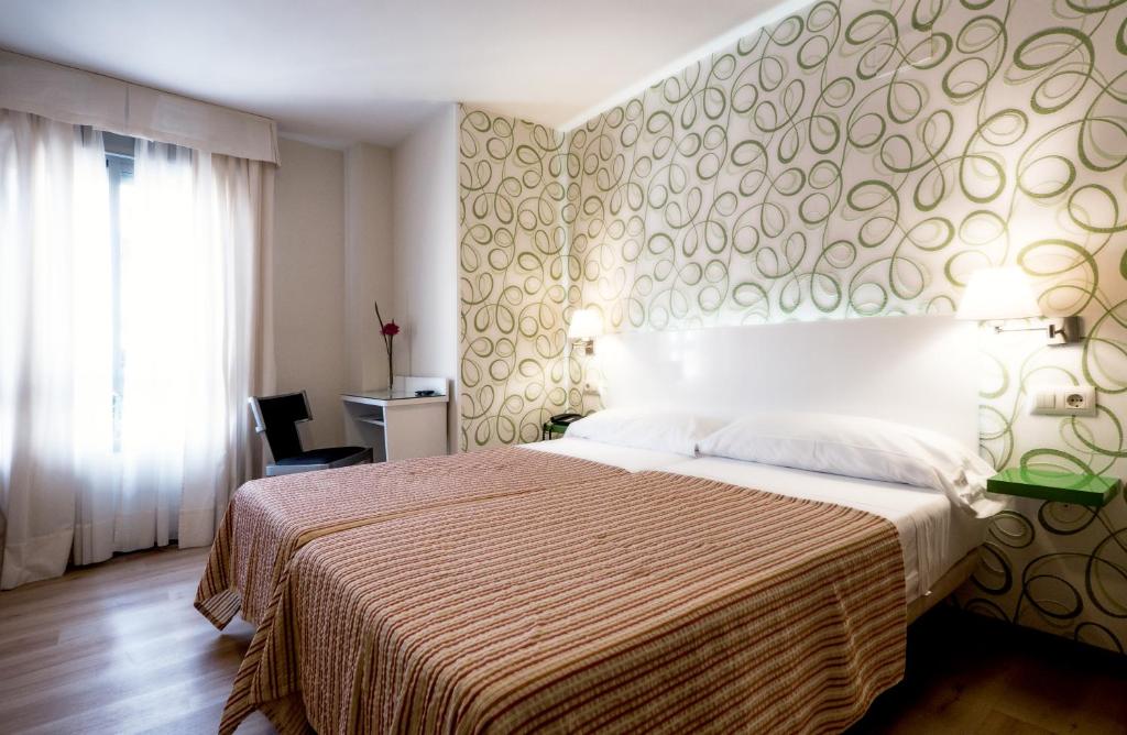 塞维利亚圣卢西亚广场酒店的一间卧室配有一张大床,配有棕色和白色的床罩
