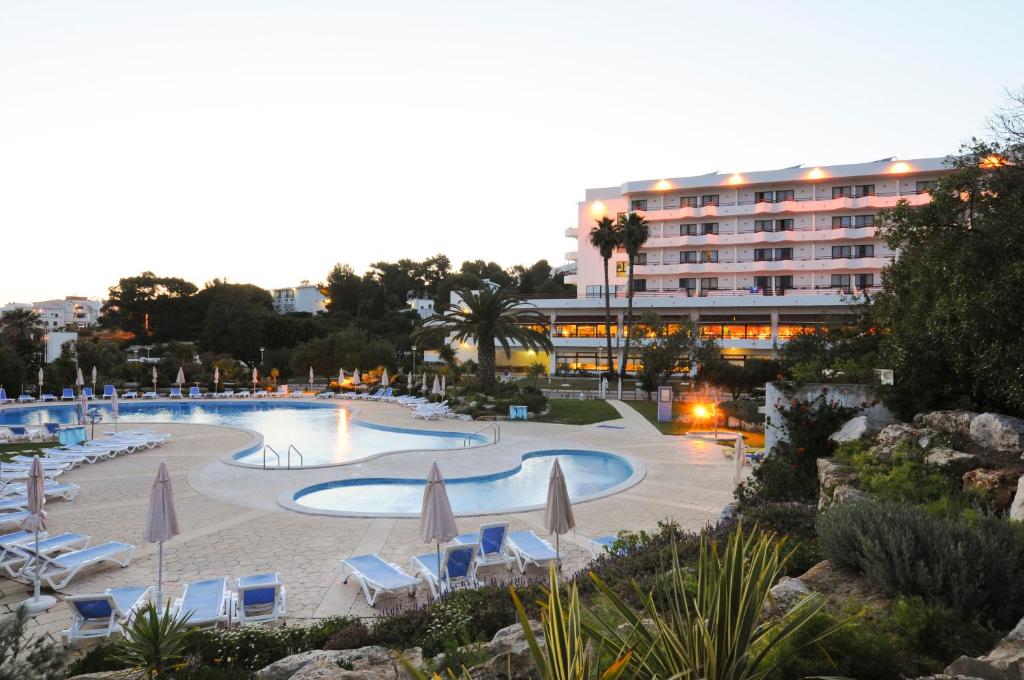 阿尔布费拉阿尔布费拉因娜酒店的一个带遮阳伞和椅子的大型游泳池以及酒店