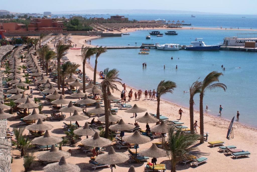 赫尔格达吉夫腾阿祖尔度假酒店的一片海滩上放着一把遮阳伞和棕榈树