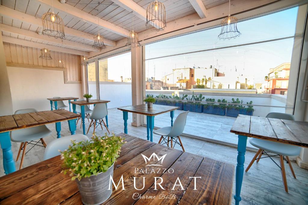 莫诺波利Palazzo Murat B&B的餐厅设有桌椅和大窗户。