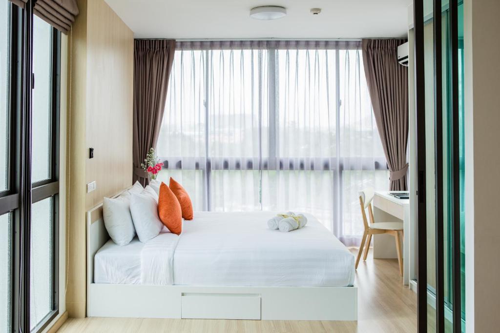 普吉镇康内斯特公寓式酒店的一间卧室配有一张带书桌的床和窗户。