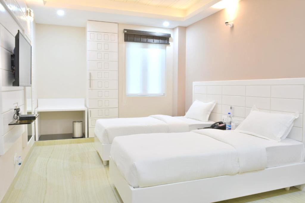 新德里Hotel Tara Palace Redfort的白色的客房配有两张床和电视。