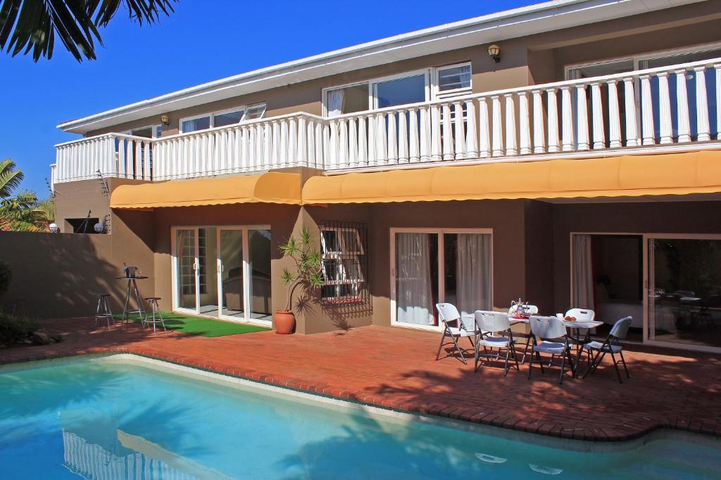 德班Durban Manor Guest House的一座带游泳池和桌椅的房子