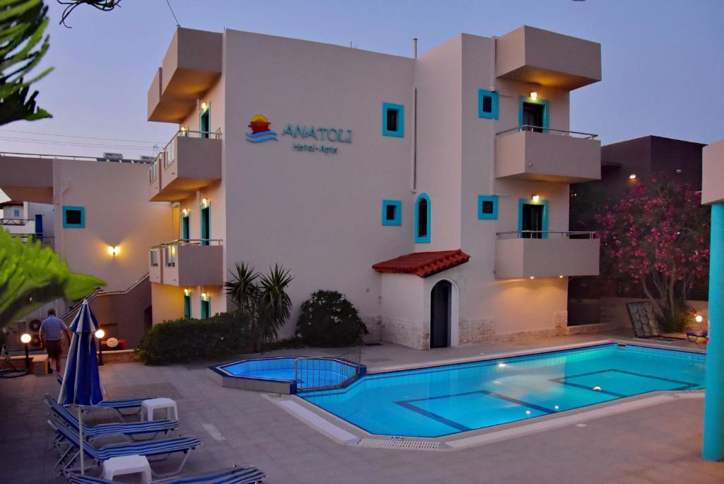 斯塔里斯Hotel Anatoli Apartments的大楼前设有游泳池的酒店