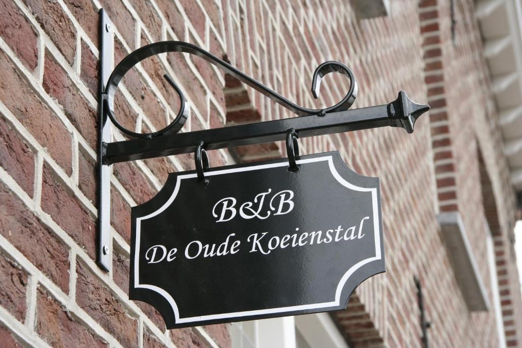 SchimmertDe Oude Koeienstal的挂在砖楼边的黑色标志