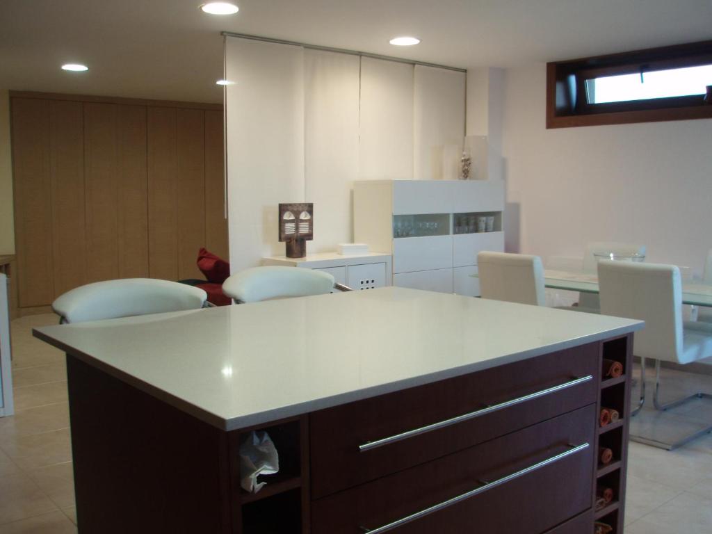 桑亨霍Mar y Sol的厨房配有白色的柜台和一些椅子