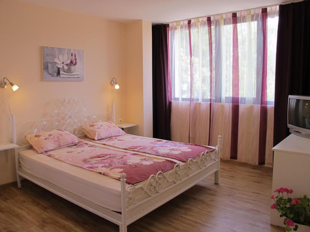 科泰尔Guest House & Bistro Lefterova的一间卧室配有一张带粉色床单的床和一扇窗户。