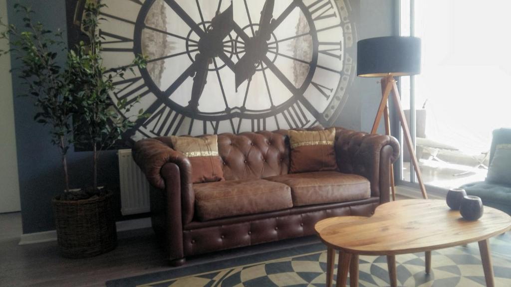维纳德马Apartamento Boutique Viña del Mar的客厅里设有一张棕色沙发,配有大时钟