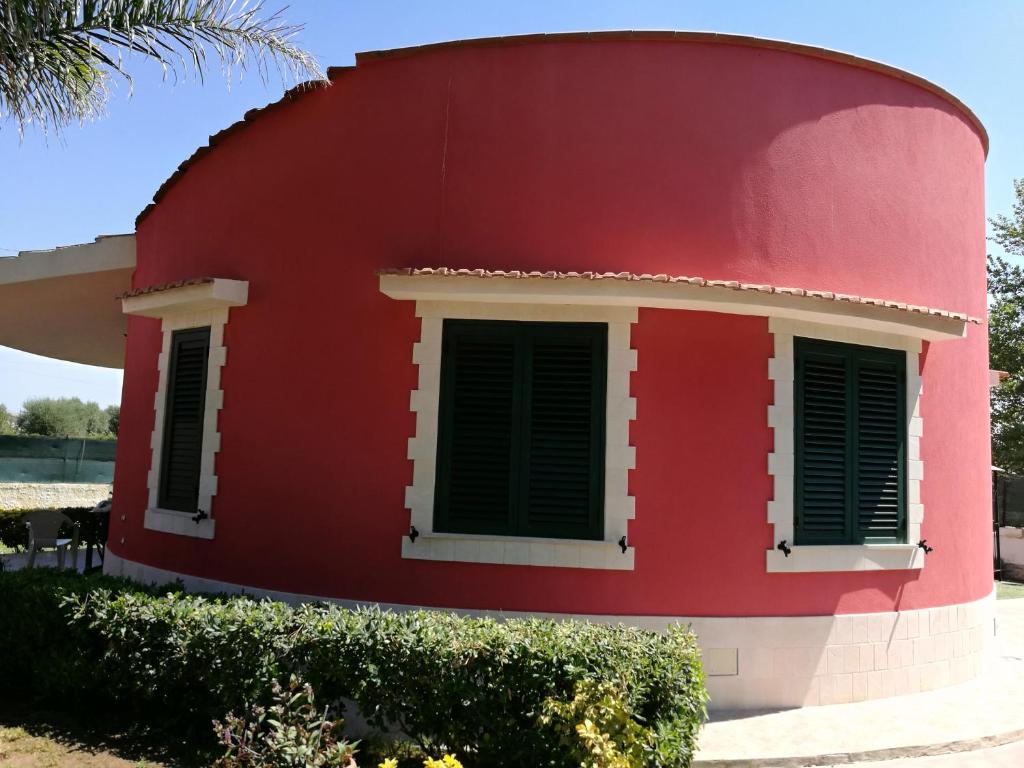 阿沃拉Villa Costanzo al mare的红色的房子,设有绿色百叶窗