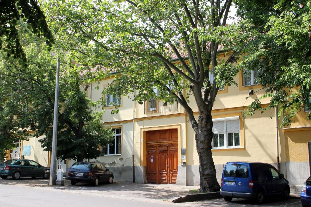 埃格尔Veva Apartman - Eger Magánszálláshely的一座带木门的建筑,前面有汽车停放