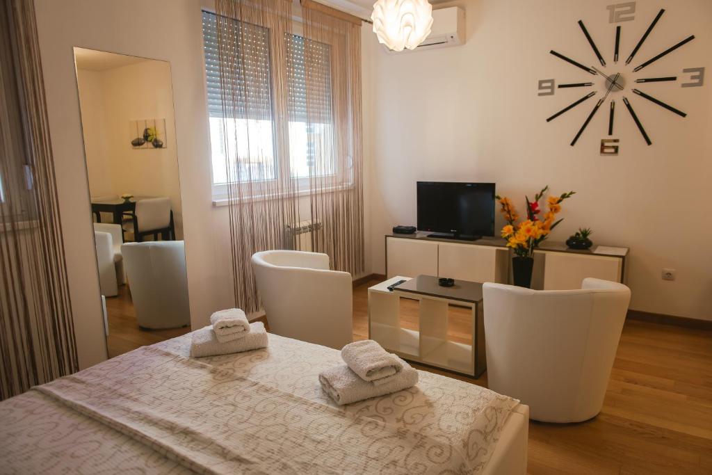 贝尔格莱德Maja Apartment的客厅配有桌椅和时钟