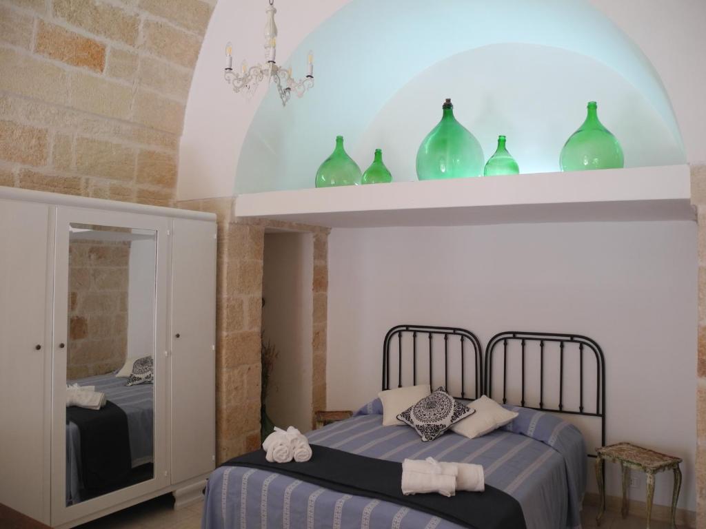 滨海波利尼亚诺Portoncino46的一间卧室设有两张床铺,架子上摆放着绿花瓶