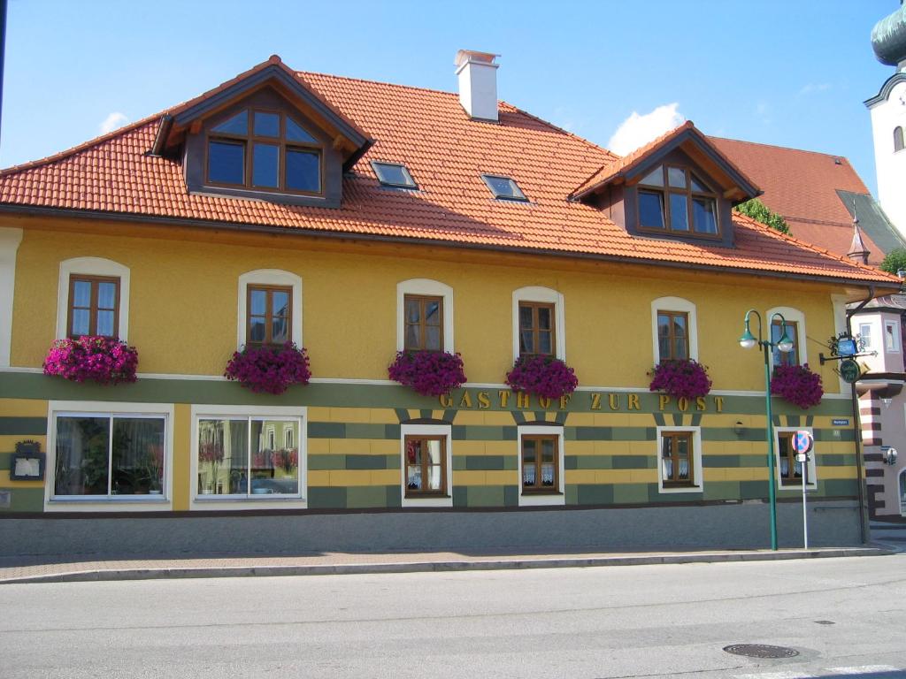 施奥弗灵Gasthof zur Post的黄色的建筑,花朵在建筑的一侧