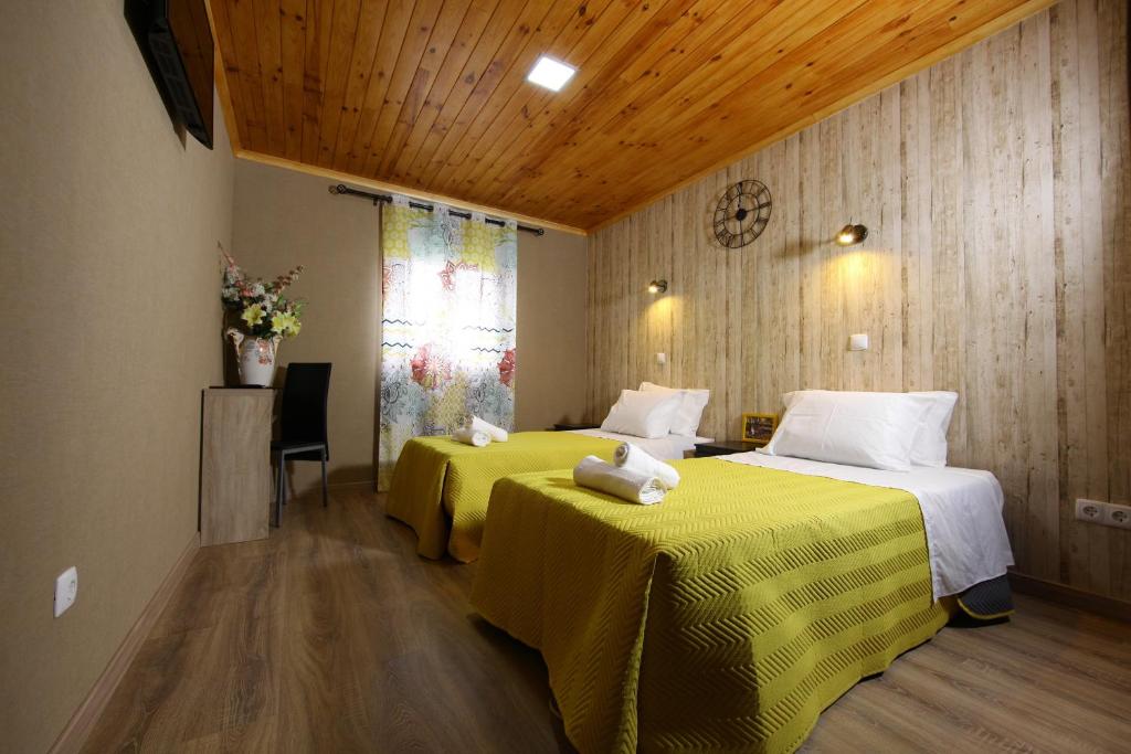 法鲁幸福旅馆的酒店客房带两张带黄床单的床