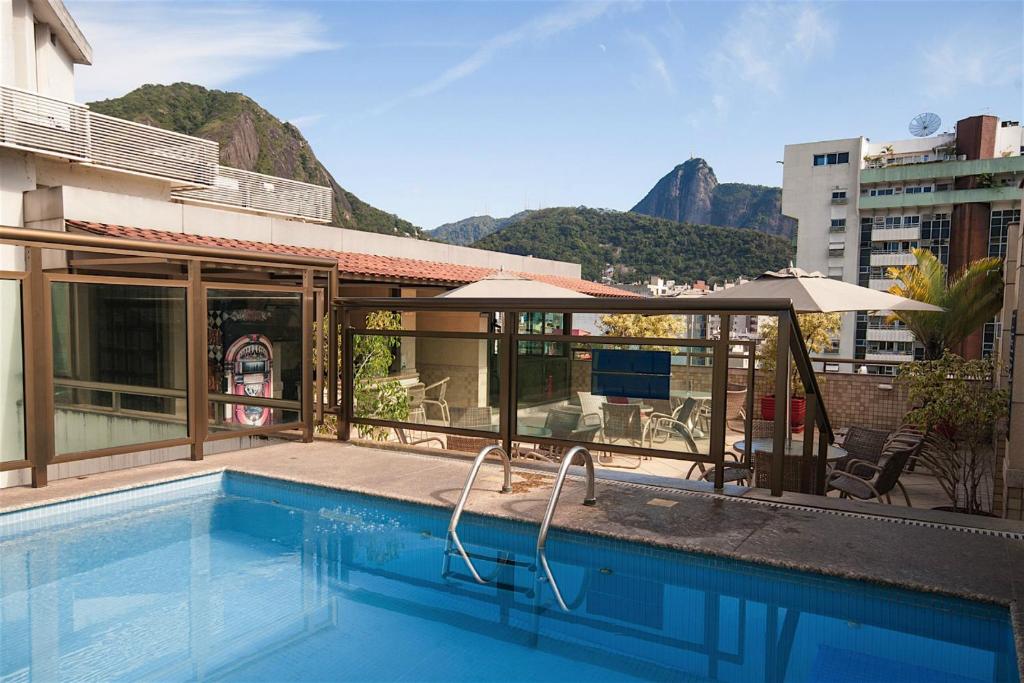 里约热内卢克帕卡巴纳马尔宫殿酒店的一座带遮阳伞的游泳池位于大楼旁