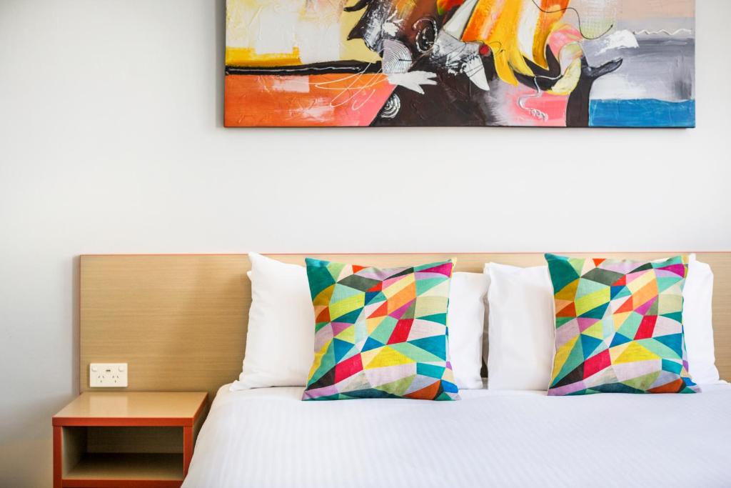 悉尼格兰维尔酒店的一张带两个枕头的床和墙上的绘画