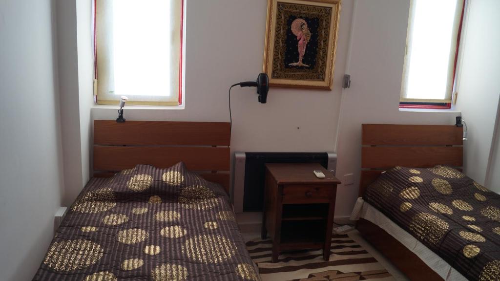 拉纳卡Destalo Court Larnaca Apartment的客房设有两张床、一张桌子和两个窗户。