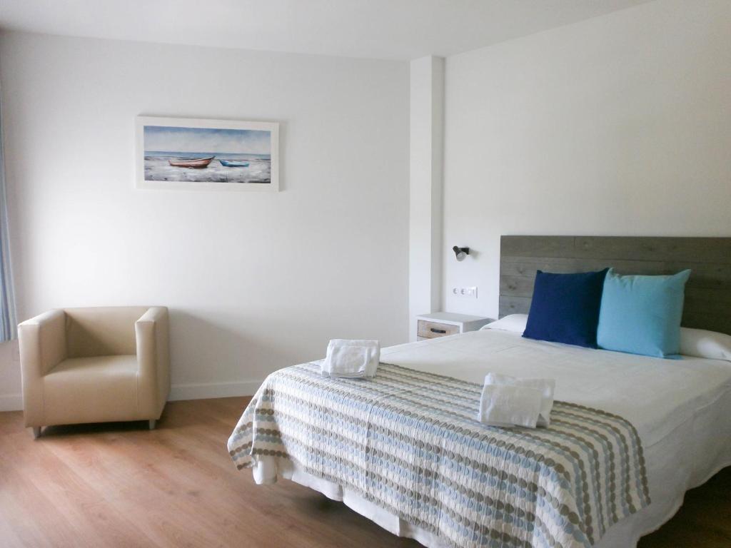 萨洛La Siesta Apartamentos的一间卧室配有一张大床和一把椅子