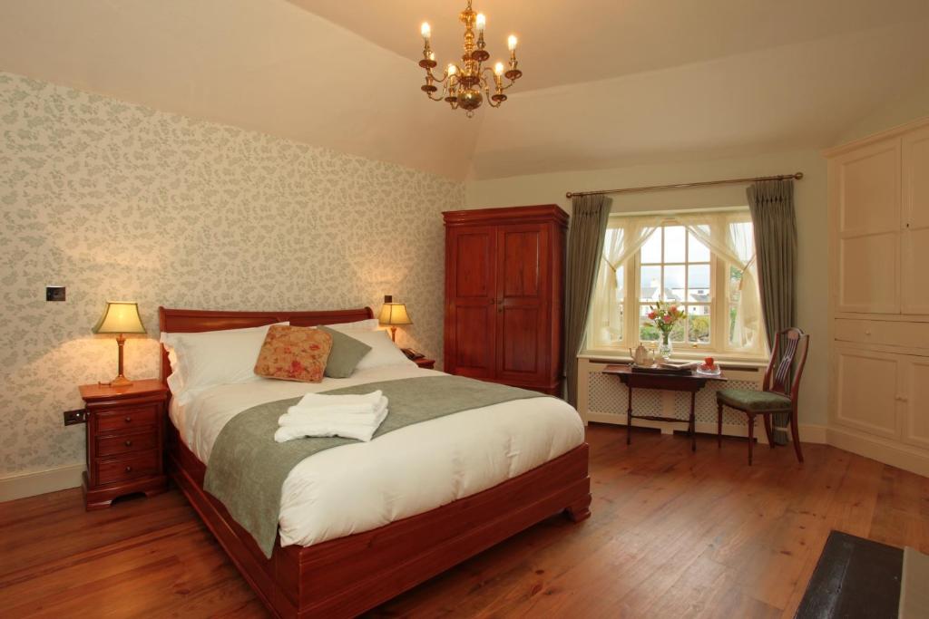 戈尔韦考瑞比旅馆的一间卧室配有一张床、一张书桌和一个吊灯。