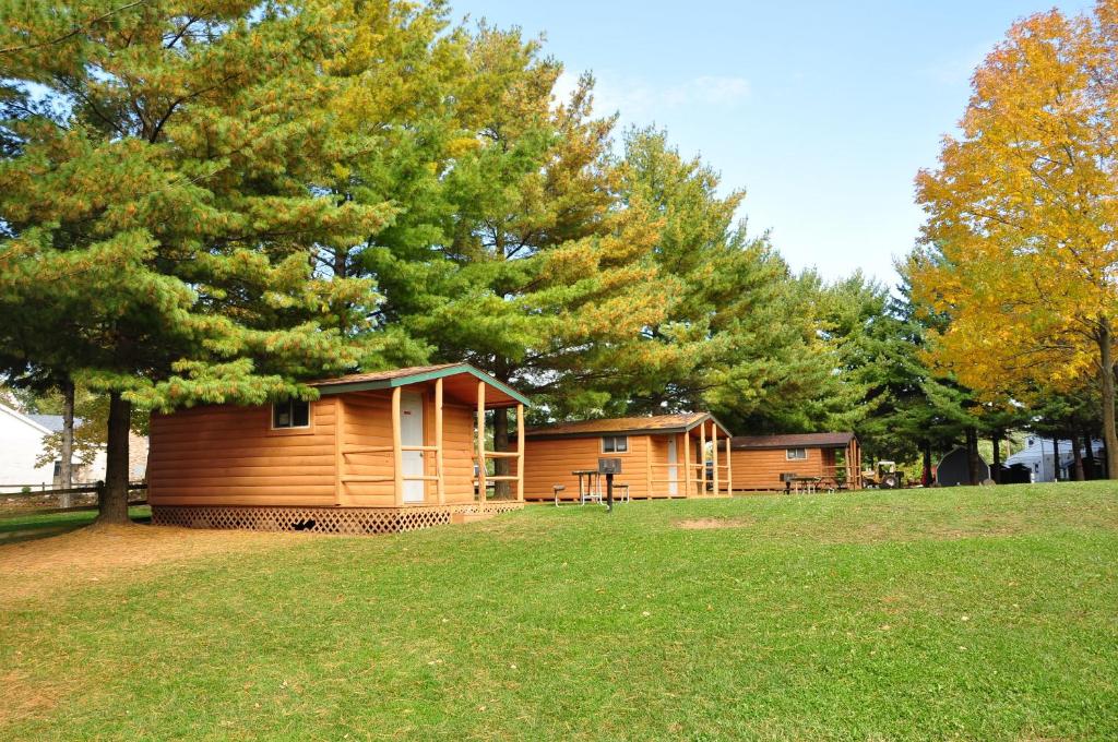 Elkhart LakePlymouth Rock Camping Resort One-Bedroom Cabin 6的公园里种有树木和草的小屋