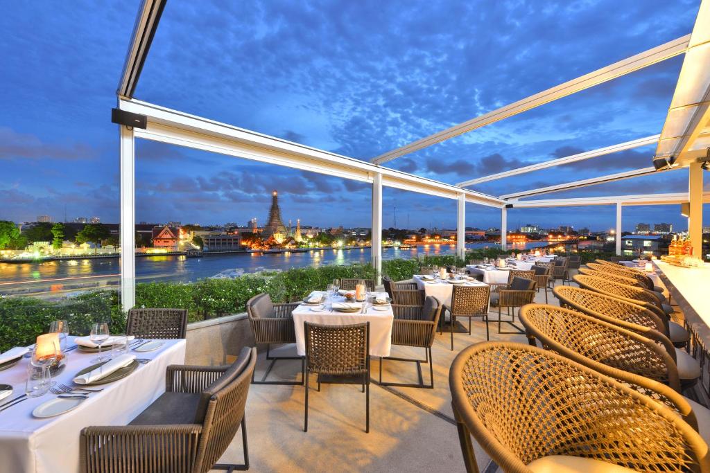 曼谷曼谷里瓦阿伦酒店 - SHA Extra Plus的一间带桌椅并享有河景的餐厅