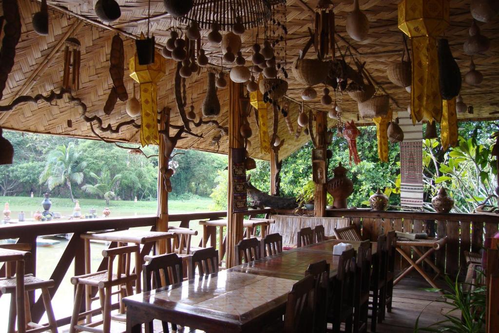 清莱班苏安杨特拉乡村民宿的餐厅设有木桌、椅子和大窗户。