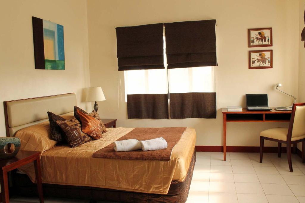马尼拉卡萨丽塔公寓式酒店的一间卧室配有一张带书桌的床和窗户。