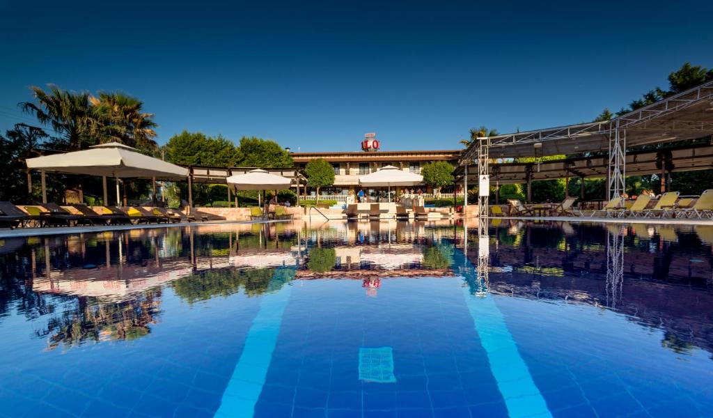 塞尔米Avalon Airport Hotel Thessaloniki的度假村的游泳池,配有椅子和遮阳伞