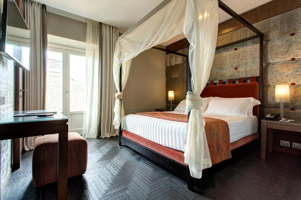 罗马Mascagni Luxury Rooms & Suites的一间卧室配有一张天蓬床和一张书桌