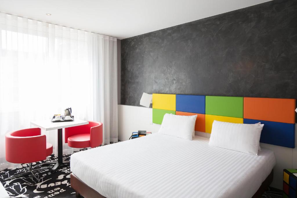 拉卢维耶尔三星酒店的卧室配有白色的床和色彩缤纷的墙壁