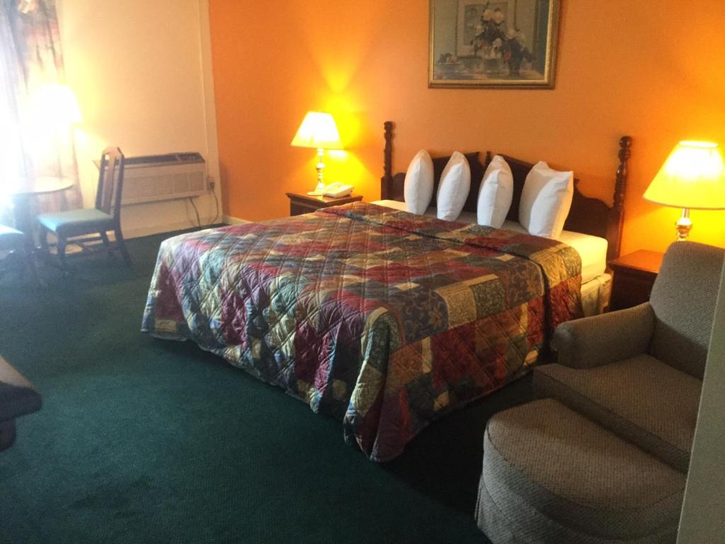 兰伯顿Budget inn的配有一张床和一把椅子的酒店客房