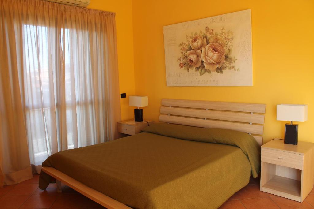 菲乌米奇诺朱莉公寓式酒店的黄色卧室配有一张床和两盏灯