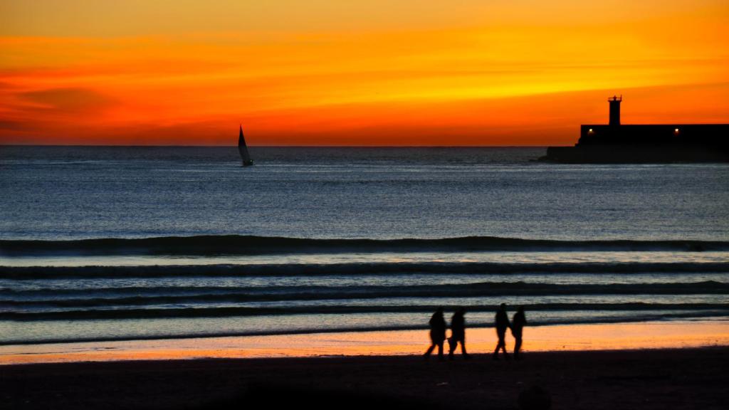 马托西纽什Porto's City Park & Surf Beach Rooms的一群人日落时在海滩上散步