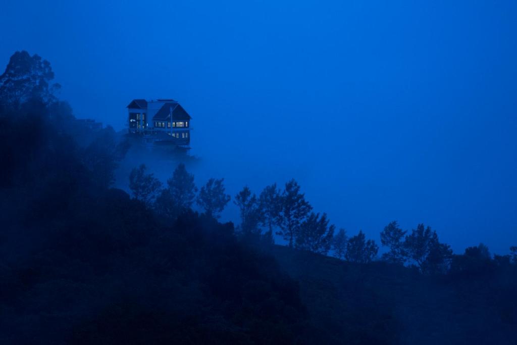 蒙纳Fragrant Nature Munnar - A Five Star Classified Hotel的雾中山顶的房屋