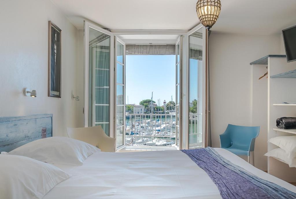 拉罗谢尔Hotel La Marine, Vieux Port的卧室设有一张白色大床和大窗户