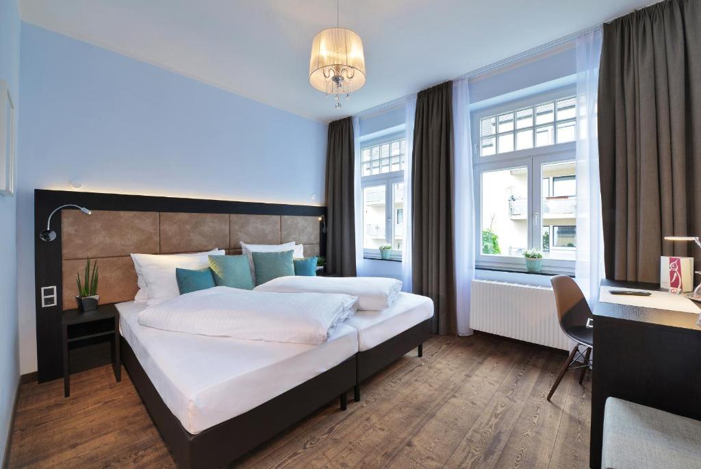 科隆UHU Gästehaus Superior的卧室配有一张床、一张书桌和窗户。