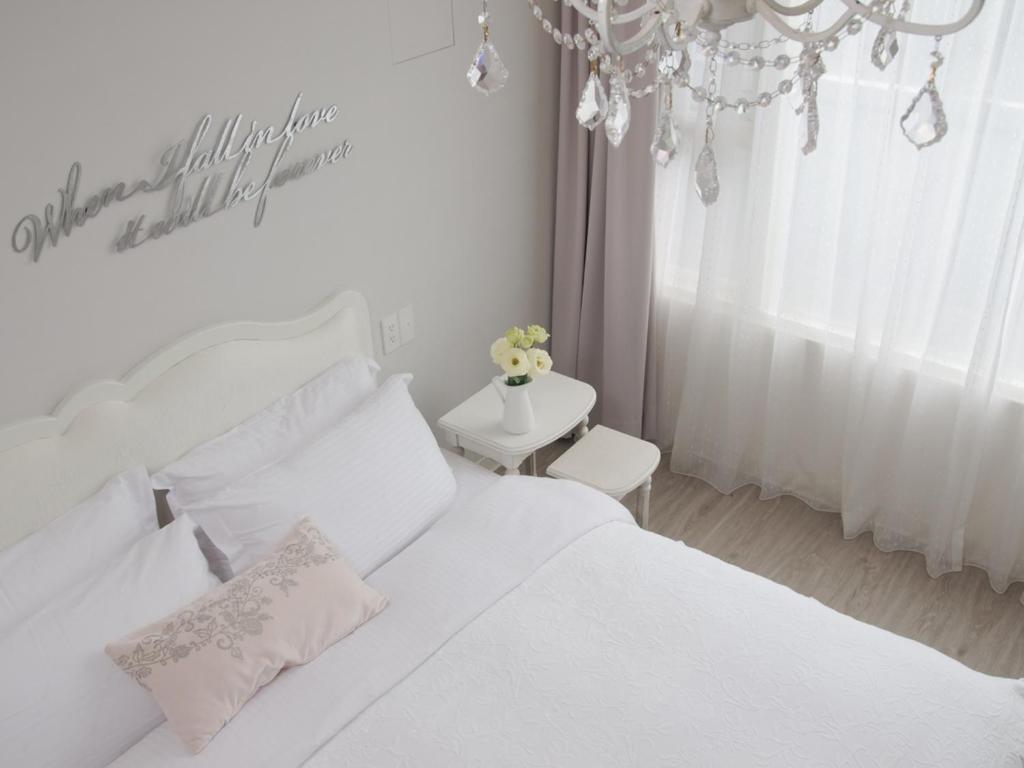 罗东镇White Truffle B&B的白色卧室配有白色的床和吊灯