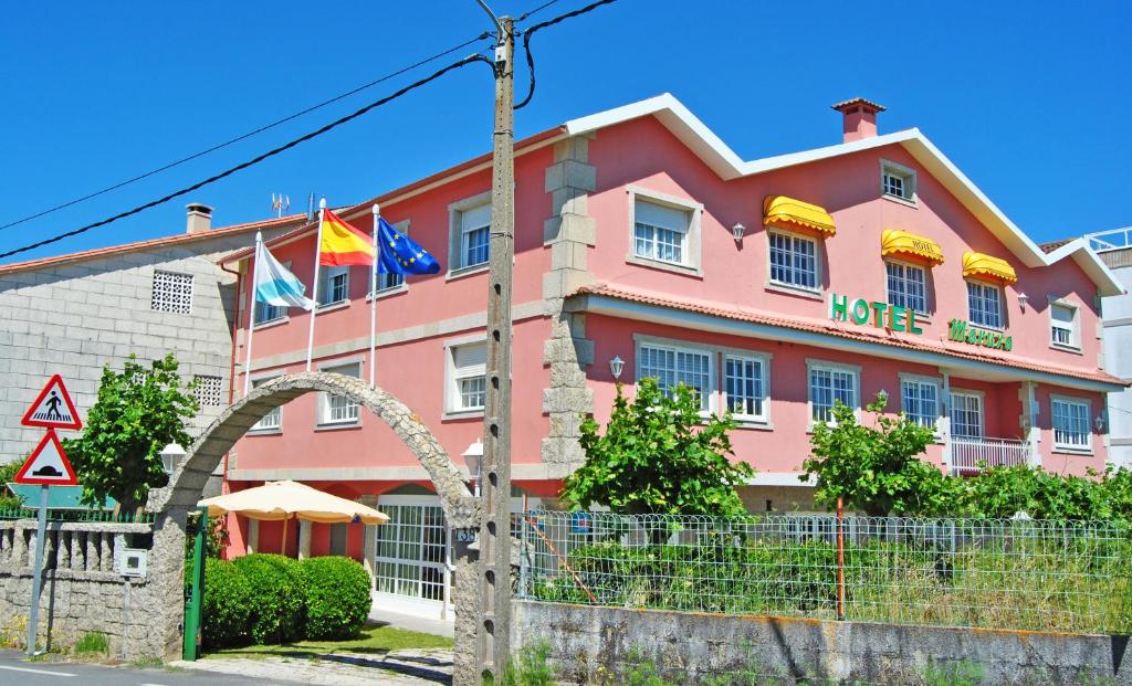 阿兰扎达Hotel Maruxa的前面有旗帜的粉红色建筑