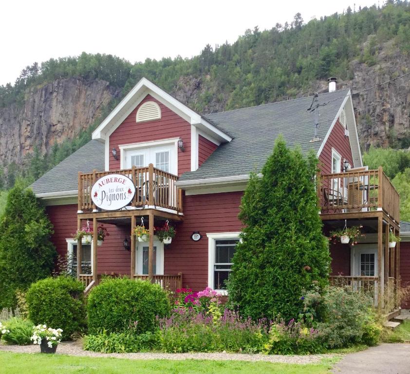 Petit-SaguenayB&B Les Deux Pignons的红色的房子,上面有标志
