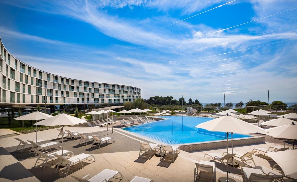 罗维尼Maistra Select Family Hotel Amarin的一个带游泳池、椅子和遮阳伞的酒店
