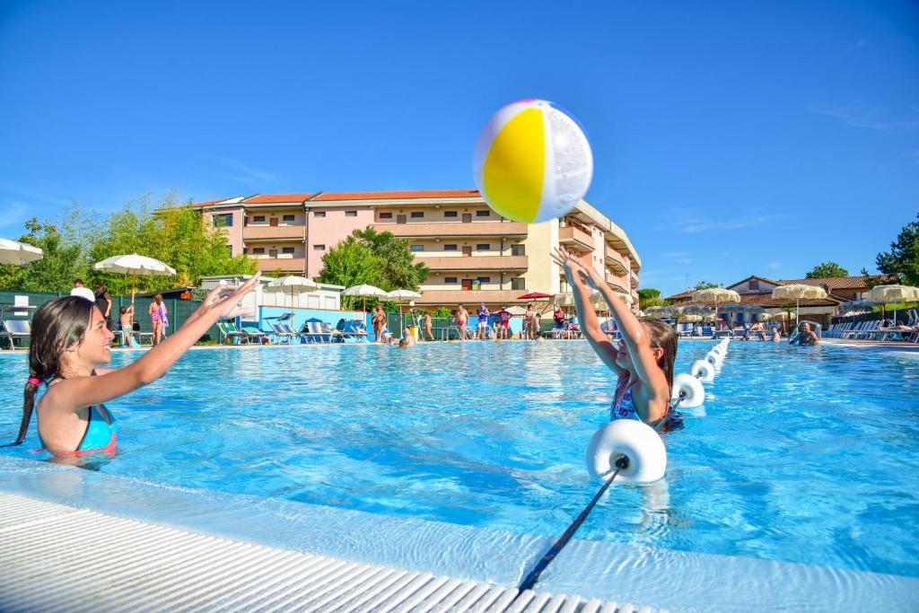 丽都阿德里亚诺Aparthotel Costa Paradiso的两个女孩在游泳池玩排球