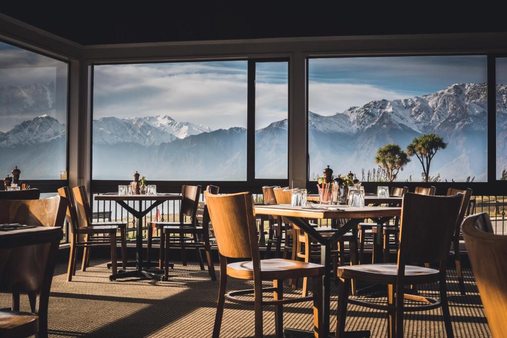 瓦纳卡Hawea Hotel的餐厅配有桌椅,位于山脉的背景中。